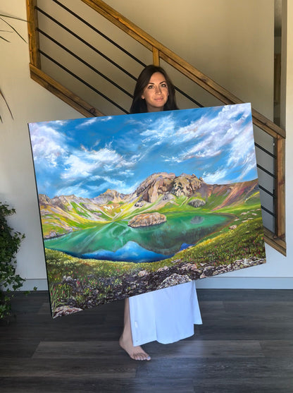 Colorado artist holding landscape painting of Island Lake, an alpine Lake in the rocky mountains.